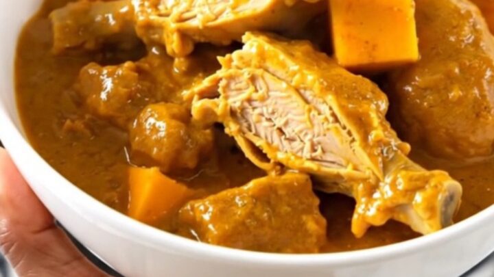 A slow cooker filled with raw turkey, red kuri squash, and coconut milk ready to be cooked.