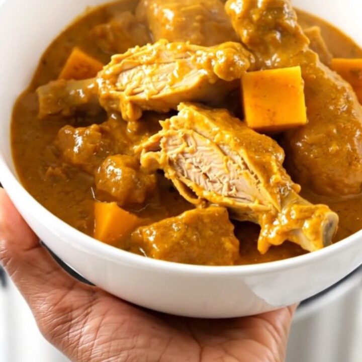 A slow cooker filled with raw turkey, red kuri squash, and coconut milk ready to be cooked.