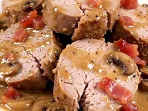 Filet mignon en médaillons nappé d'une sauce crémeuse aux champignons et lardons sur une assiette blanche.