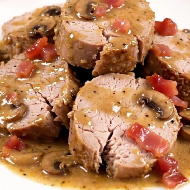Filet mignon en médaillons nappé d'une sauce crémeuse aux champignons et lardons sur une assiette blanche.