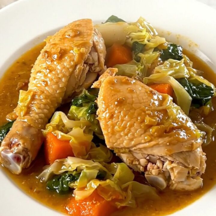 Slow cooker chicken and cabbage stew in a black oval pot on a speckled countertop.
