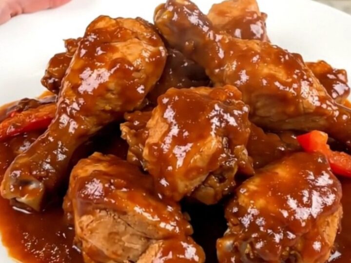 A black slow cooker filled with chicken thighs, colorful bell peppers, onions, and a rich tomato sauce.