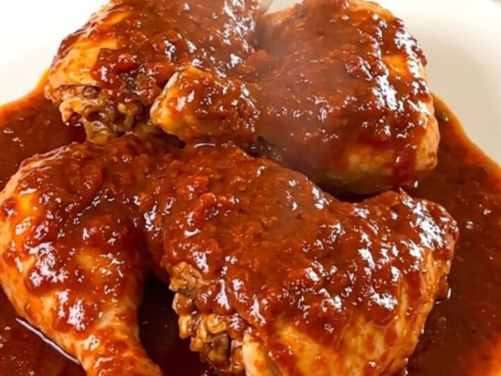 A finished dish of deviled chicken with a glossy sauce served on a white plate.