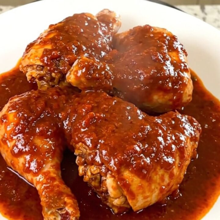 A finished dish of deviled chicken with a glossy sauce served on a white plate.