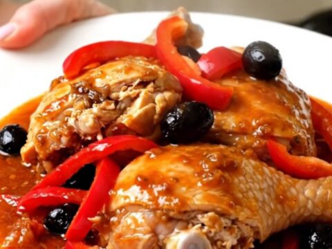 Vue de dessus d'un poulet catalan mijoté avec des poivrons rouges et des olives noires dans une mijoteuse.