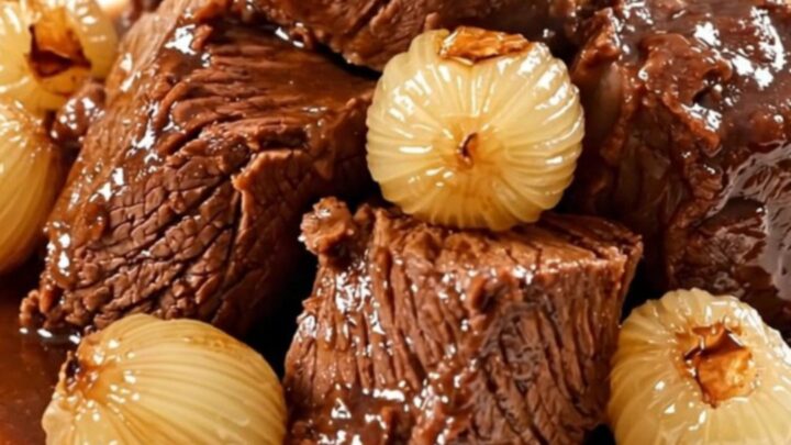 Bœuf braisé fondant servi dans une assiette blanche avec ses oignons grelots.