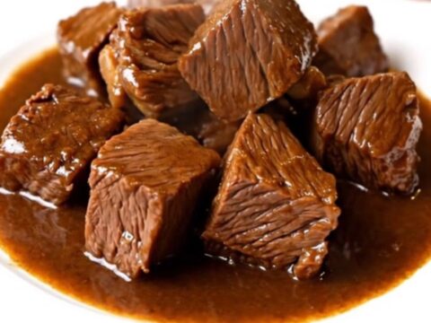 Bœuf fondant mijoté dans une sauce sombre et brillante au vin rouge et ail noir dans une mijoteuse.