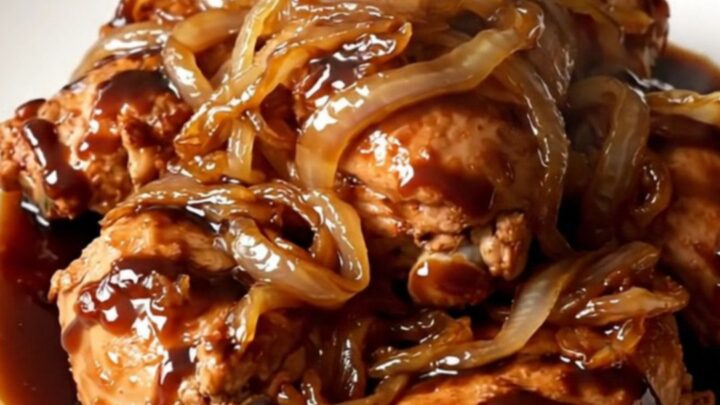 Vue en plongée d'une mijoteuse contenant des cuisses de poulet, des oignons et une sauce balsamique sombre.