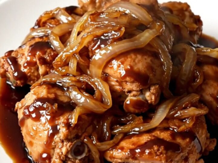Vue en plongée d'une mijoteuse contenant des cuisses de poulet, des oignons et une sauce balsamique sombre.