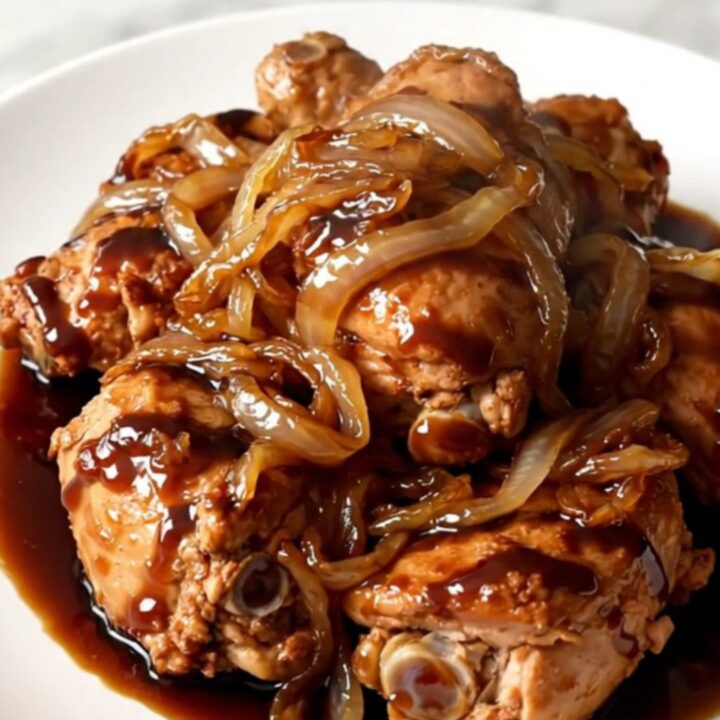 Vue en plongée d'une mijoteuse contenant des cuisses de poulet, des oignons et une sauce balsamique sombre.