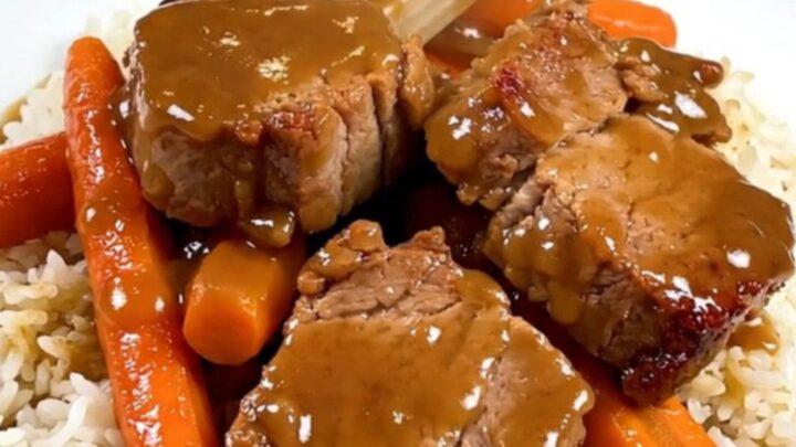 A top-down view of raw pork, carrots, and shallots in a slow cooker insert before cooking.