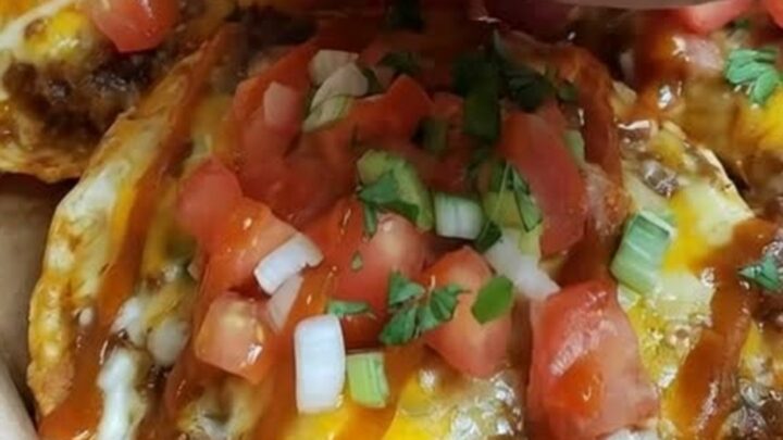 A crispy Mexican pizza topped with melted cheese, red sauce, fresh diced tomatoes, and sliced green onions.