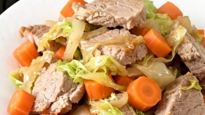 Échine de porc fondante avec des carottes et du chou dans une mijoteuse noire.