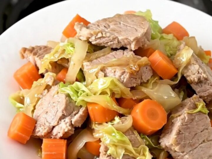 Échine de porc fondante avec des carottes et du chou dans une mijoteuse noire.