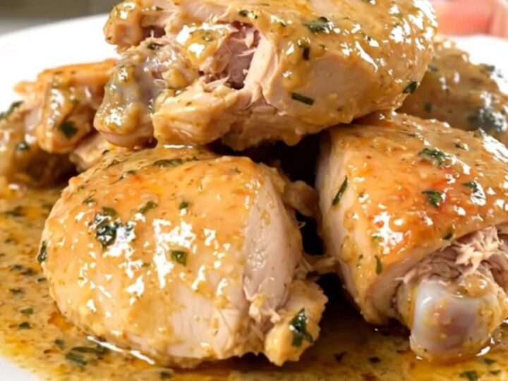 Cuisses de poulet tendres nappées d'une sauce onctueuse à la sauge dans une assiette blanche.