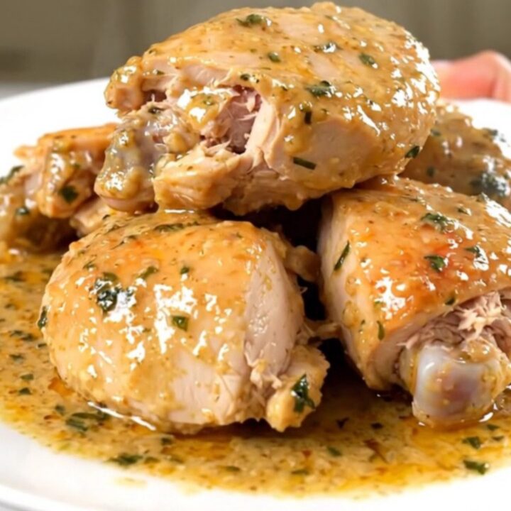 Cuisses de poulet tendres nappées d'une sauce onctueuse à la sauge dans une assiette blanche.