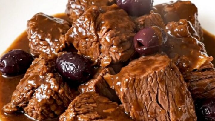 Daube de bœuf brillante et fondante servie dans une assiette blanche avec des olives et de la sarriette.