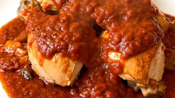 Vue de dessus d'un poulet cacciatore fumant servi dans une assiette blanche élégante.