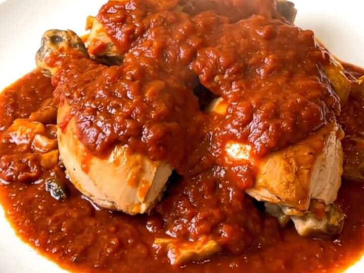 Vue de dessus d'un poulet cacciatore fumant servi dans une assiette blanche élégante.