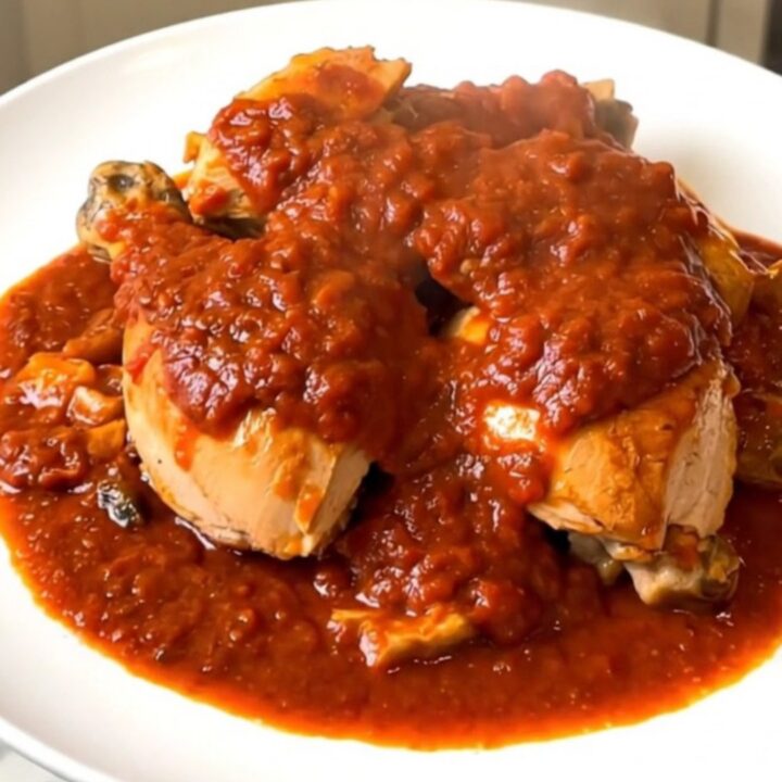 Vue de dessus d'un poulet cacciatore fumant servi dans une assiette blanche élégante.