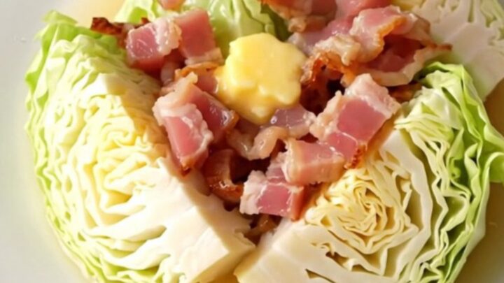 A close-up of tender, buttery green cabbage wedges topped with soft, savory bacon pieces in a slow cooker.
