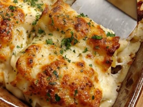 A golden, bubbling creamy garlic parmesan chicken pasta bake in a rustic ceramic pan.