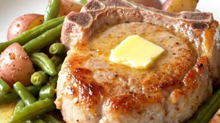 A plate featuring a tender, braised bone-in pork chop with soft green beans and baby potatoes in a light butter sauce.