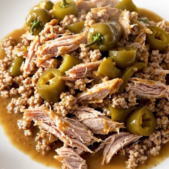 A close-up of a slow cooker filled with ground turkey, pepperoncini, and seasonings.