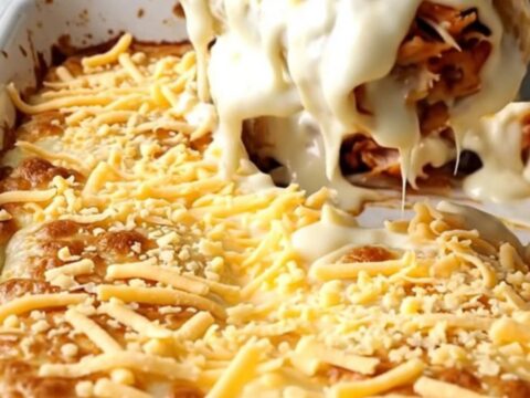 A top-down view of a rectangular baking dish filled with cheesy chicken burritos.