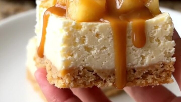 A close-up of no-bake cheesecake squares topped with apple pie filling and caramel on a baking sheet.