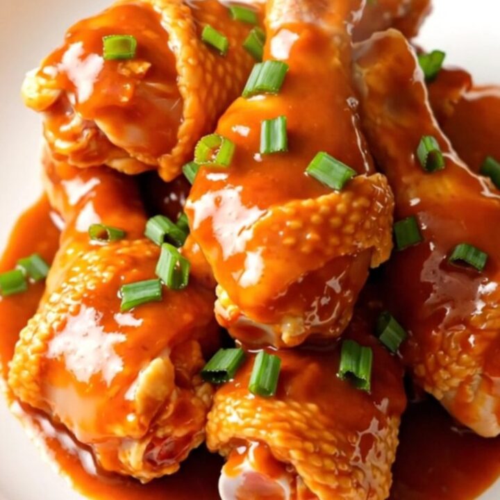 Close-up of slow cooker maple gochujang chicken drumsticks on a white plate.