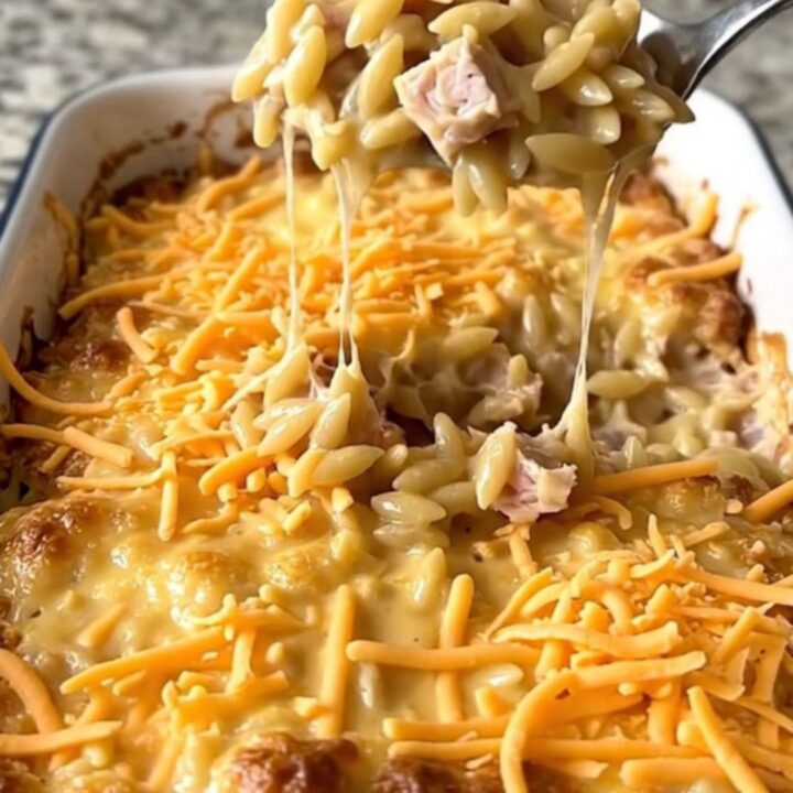 A top-down view of a creamy cheeseburger turkey orzo bake in a white rectangular baker on a granite surface.