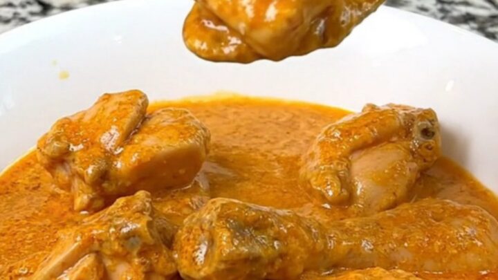 A close-up of creamy slow cooker butter chicken served in a white bowl with a spoon.