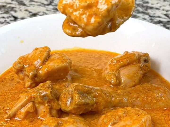 A close-up of creamy slow cooker butter chicken served in a white bowl with a spoon.