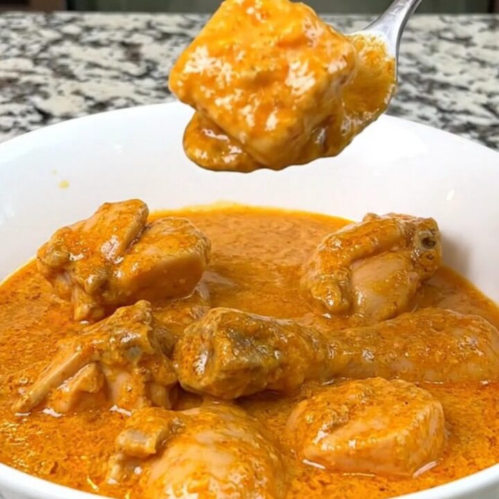 A close-up of creamy slow cooker butter chicken served in a white bowl with a spoon.