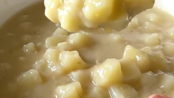 A top-down view of a slow cooker filled with creamy hash brown potato soup, showcasing the thick and hearty texture.