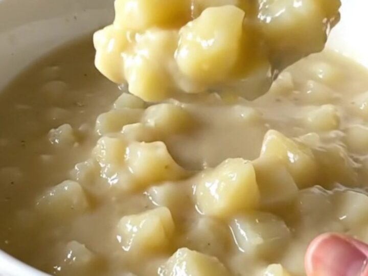 A top-down view of a slow cooker filled with creamy hash brown potato soup, showcasing the thick and hearty texture.