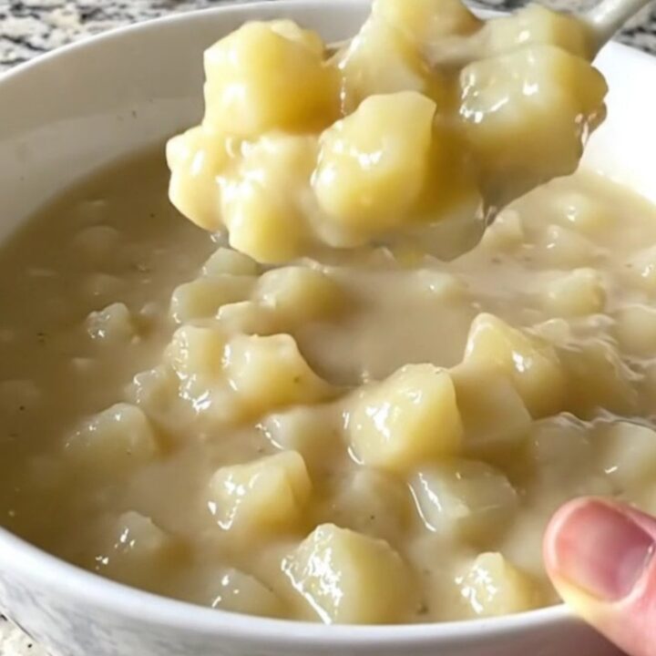 A top-down view of a slow cooker filled with creamy hash brown potato soup, showcasing the thick and hearty texture.