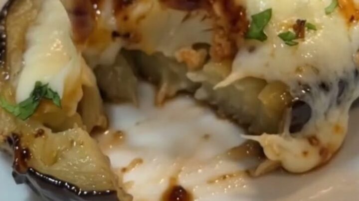 A close-up of a roasted eggplant boat topped with melted mozzarella and glossy BBQ sauce on a white plate.