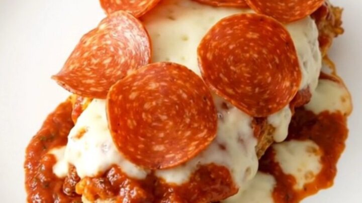 Finished slow cooker pizza chicken with melted mozzarella and pepperoni on a white plate.