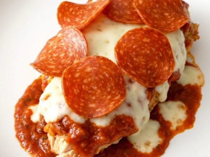 Finished slow cooker pizza chicken with melted mozzarella and pepperoni on a white plate.