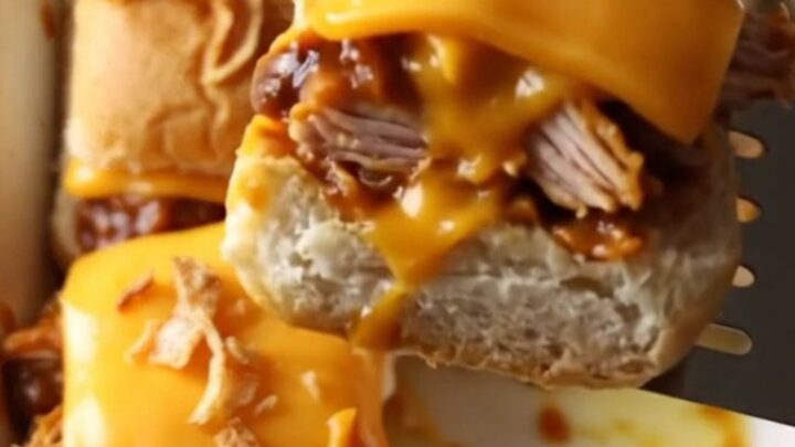 A rectangular baking dish filled with golden brown BBQ chicken sliders topped with crispy fried onions.