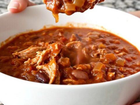 A hearty bowl of slow cooker ground turkey chili topped with fresh herbs on a kitchen counter.