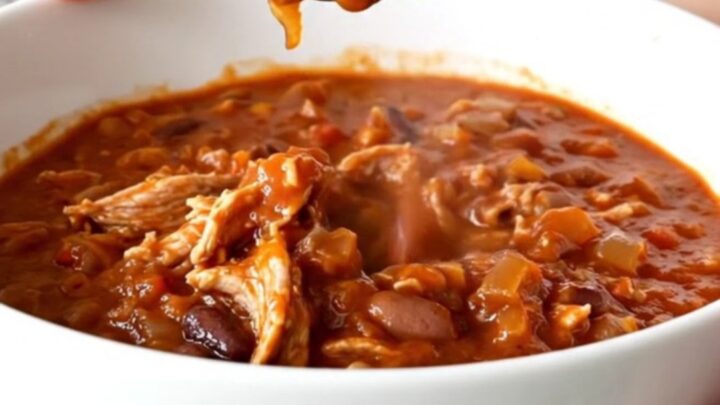 A hearty bowl of slow cooker ground turkey chili topped with fresh herbs on a kitchen counter.