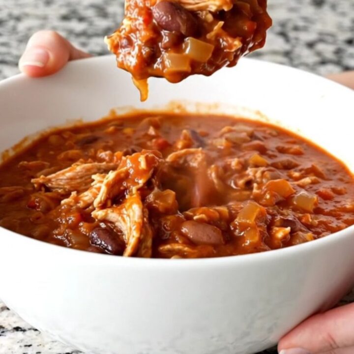 A hearty bowl of slow cooker ground turkey chili topped with fresh herbs on a kitchen counter.