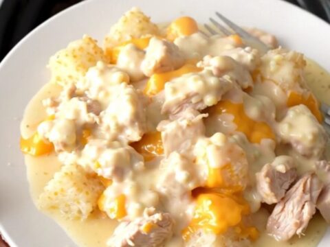 A slow cooker filled with creamy chicken and hash brown casserole, showing melted cheese and tender chicken chunks.