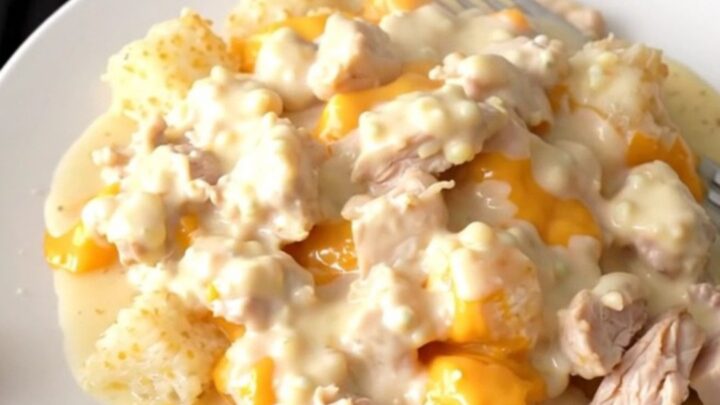 A slow cooker filled with creamy chicken and hash brown casserole, showing melted cheese and tender chicken chunks.