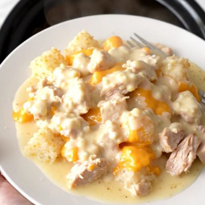A slow cooker filled with creamy chicken and hash brown casserole, showing melted cheese and tender chicken chunks.