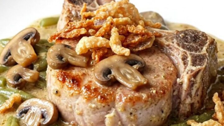 A plate of slow-cooked pork chops covered in creamy mushroom sauce and green beans with crispy onions.