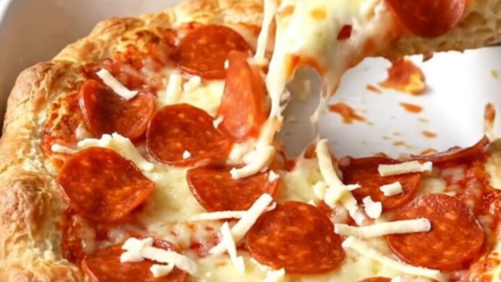 A golden brown Crescent Roll Pizza Bake in a rectangular ceramic dish, topped with bubbling cheese and pepperoni.